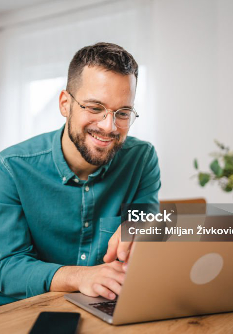 a man at the computer smiling and typing