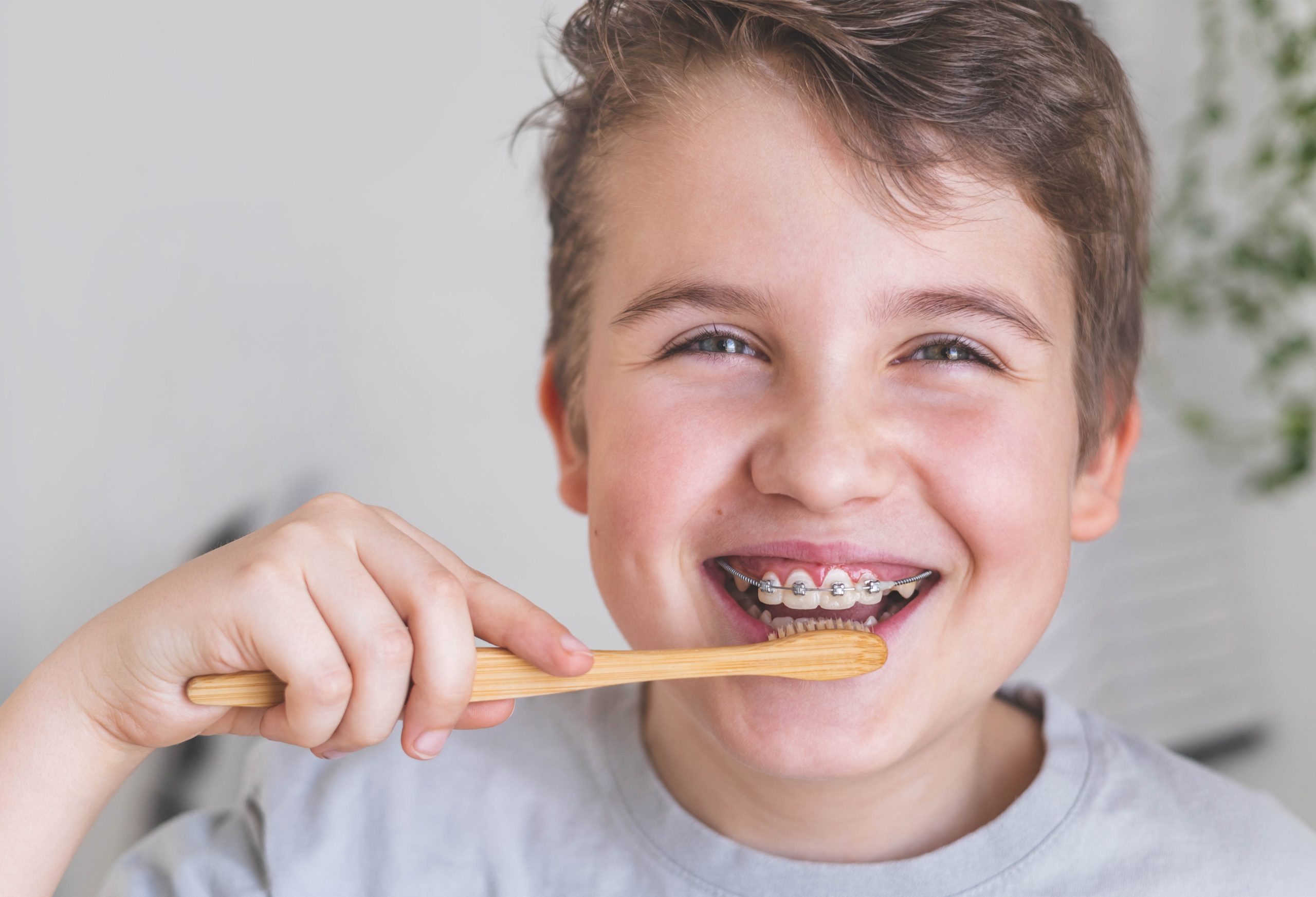 a little boy smiling while he brushes his teeth