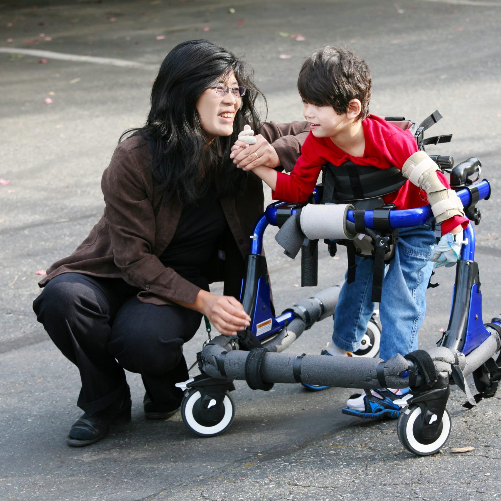 a young boy using a walking wheelchair